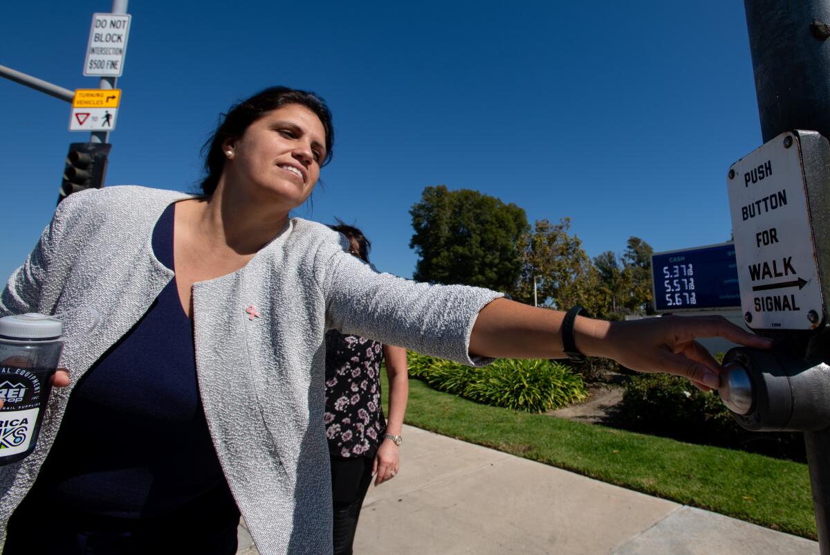 Costa Mesa Councilwoman Arlis Reynolds reaches for a pedestrian call button at Fair Drive and Fairview Road Friday, Oct. 6.