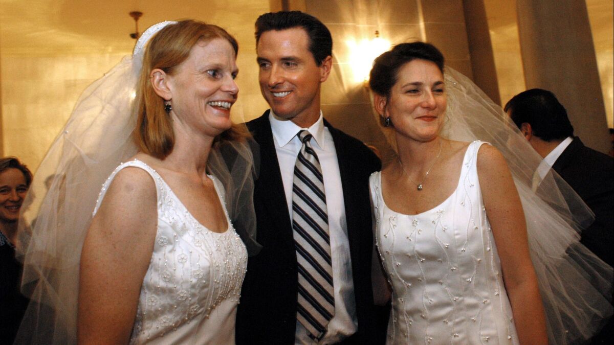 Then-San Francisco Mayor Gavin Newsom stands between newlyweds Cissie Bonini, left, and Lora Pertle at San Francisco City Hall in 2004, when he allowed nearly 4,000 same-sex couples to tie the knot in defiance of state law.