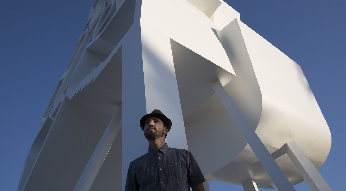Victor Montoya, 27, of San Diego rests against Jimenez Lai's "Tower of Twelve Stories" at the Coachella Valley Music and Arts Festival.