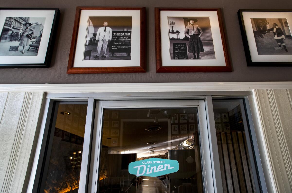 A glass door with a logo for Clark Street Diner under a row of vintage photos