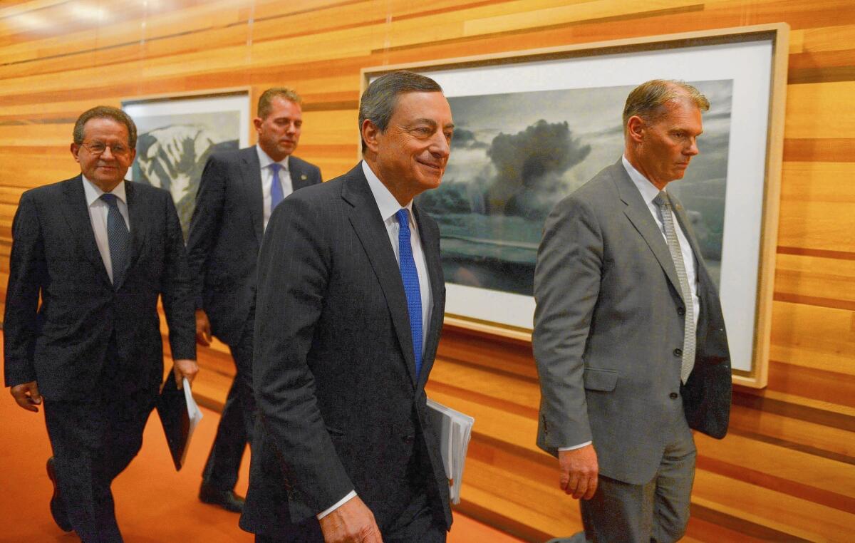 European Central Bank President Mario Draghi, center foreground, arrives for a news conference in Frankfurt, Germany.
