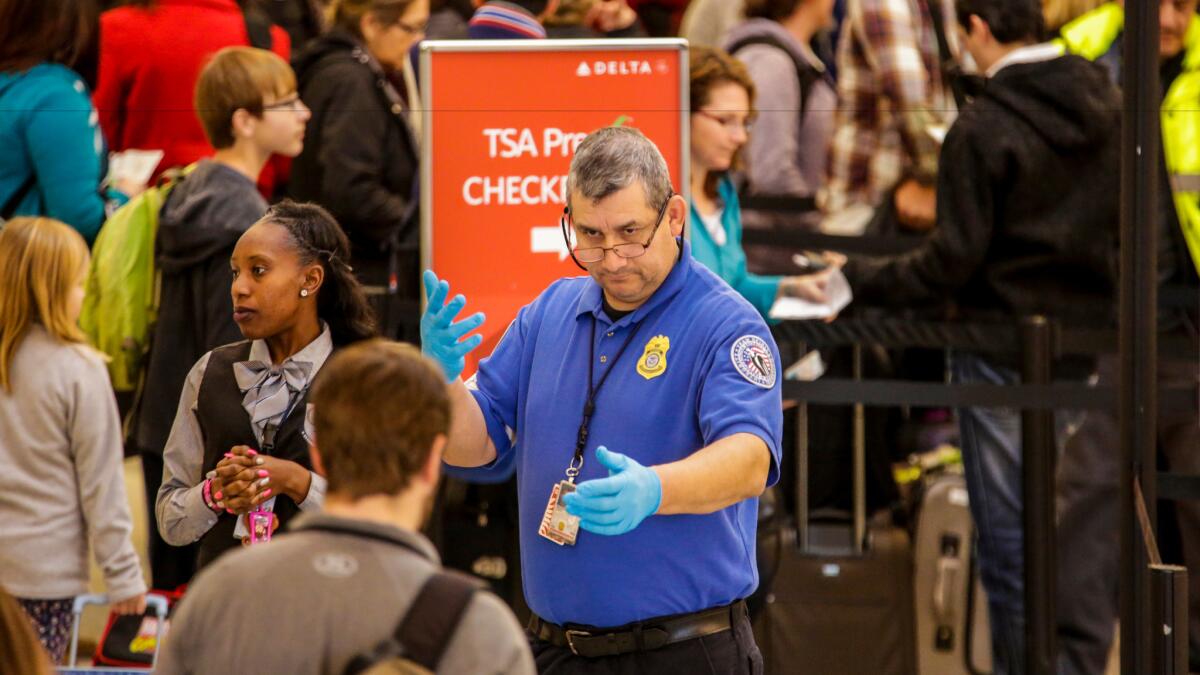 A TSA agent keeps an eye on travelers going through security at Los Angeles International Airport.