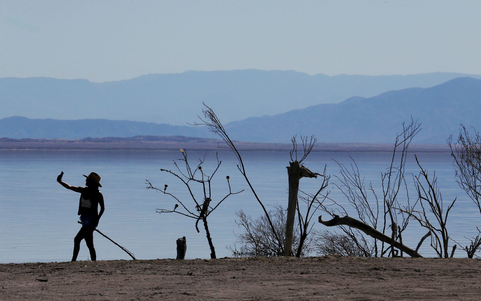 A visitor takes a selfie beside public art in Bombay Beach, a tiny community on the Salton Sea.