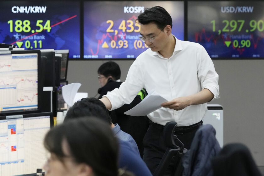 A currency trader works near the screens showing the Korea Composite Stock Price Index (KOSPI), center, and the foreign exchange rate between U.S. dollar and South Korean won, right, at the foreign exchange dealing room of the KEB Hana Bank headquarters in Seoul, South Korea, Wednesday, March 29, 2023. Asian stocks were mixed Wednesday as anxiety about the global financial system began to fade following three high-profile bank failures.(AP Photo/Ahn Young-joon)