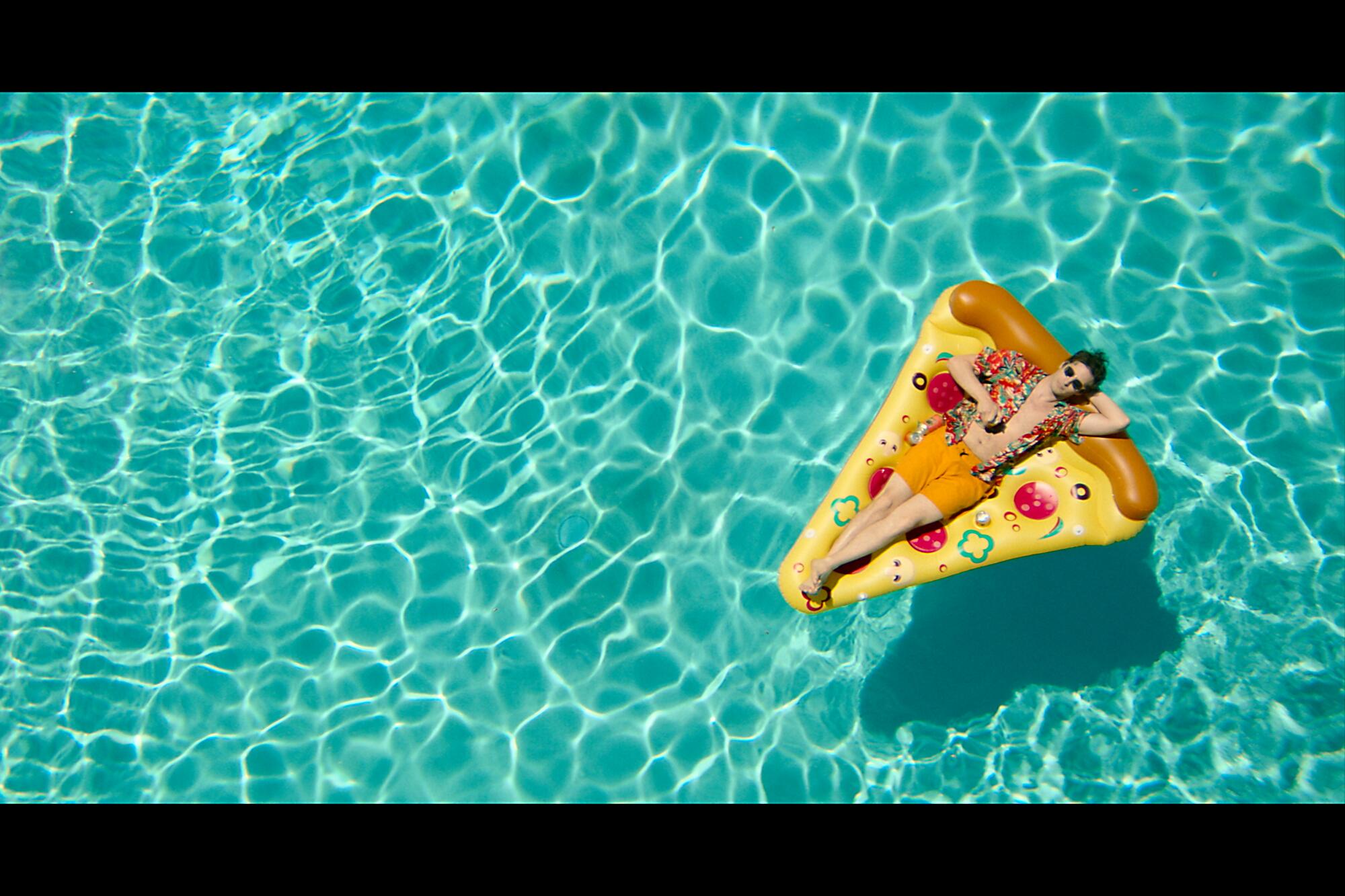 Andy Samberg lounges on a pizza-shaped float in a scene from "Palm Springs."  