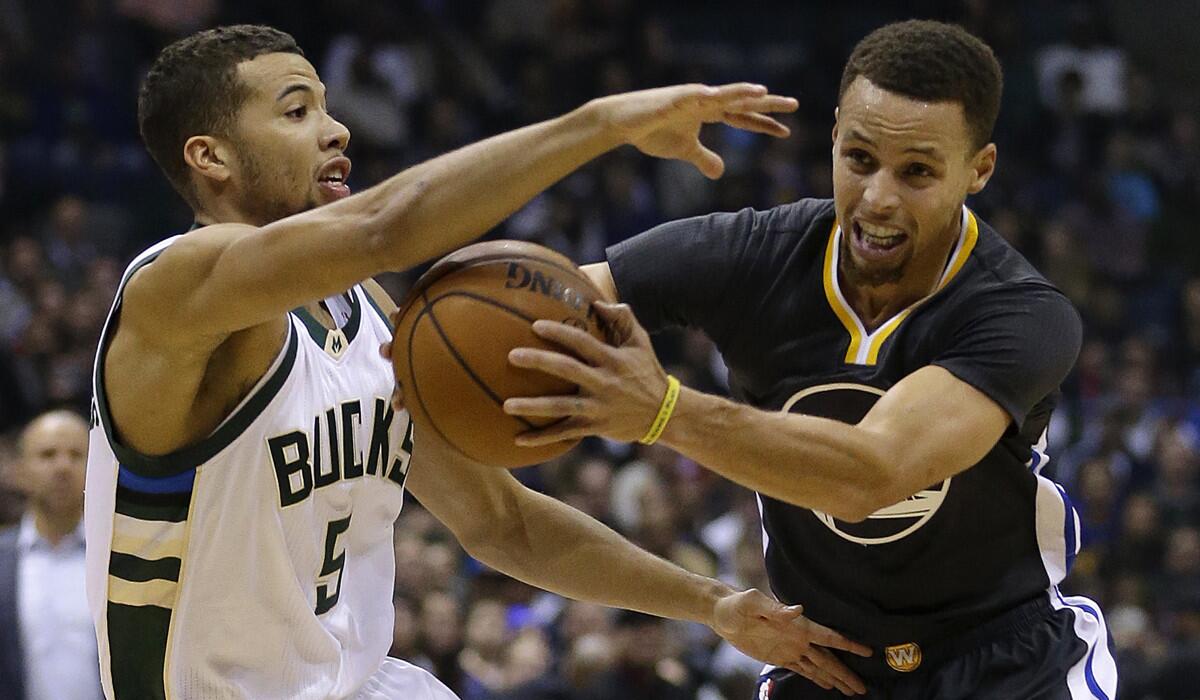 Golden State Warriors' Stephen Curry, right, drives against Milwaukee Bucks' Michael Carter-Williams, left, during the first half on Saturday.