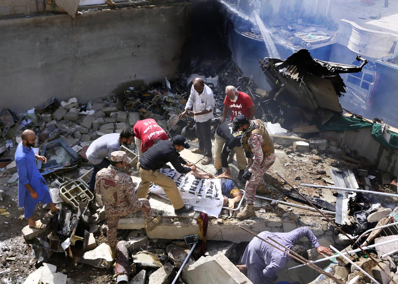 Workers prepare to remove the body of a victim removed from the wreckage of an airliner that crashed in a neighborhood near the Karachi, Pakistan, airport on Friday.