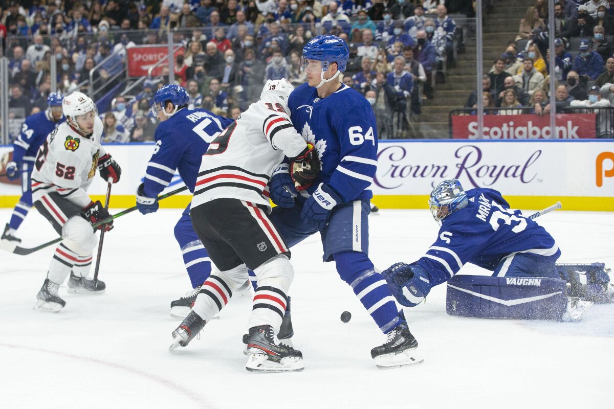 Toronto Maple Leafs goaltender Petr Mrazek, right, gets down to make a save in front of, from left to right, Chicago Blackhawks' Reese Johnson and Maple Leafs' Kristians Rubins as Blackhawks' Jonathan Toews and Maple Leafs' David Kampf battle during first-period NHL hockey game action in Toronto, Saturday, Dec. 11, 2021. (Chris Young/The Canadian Press via AP)