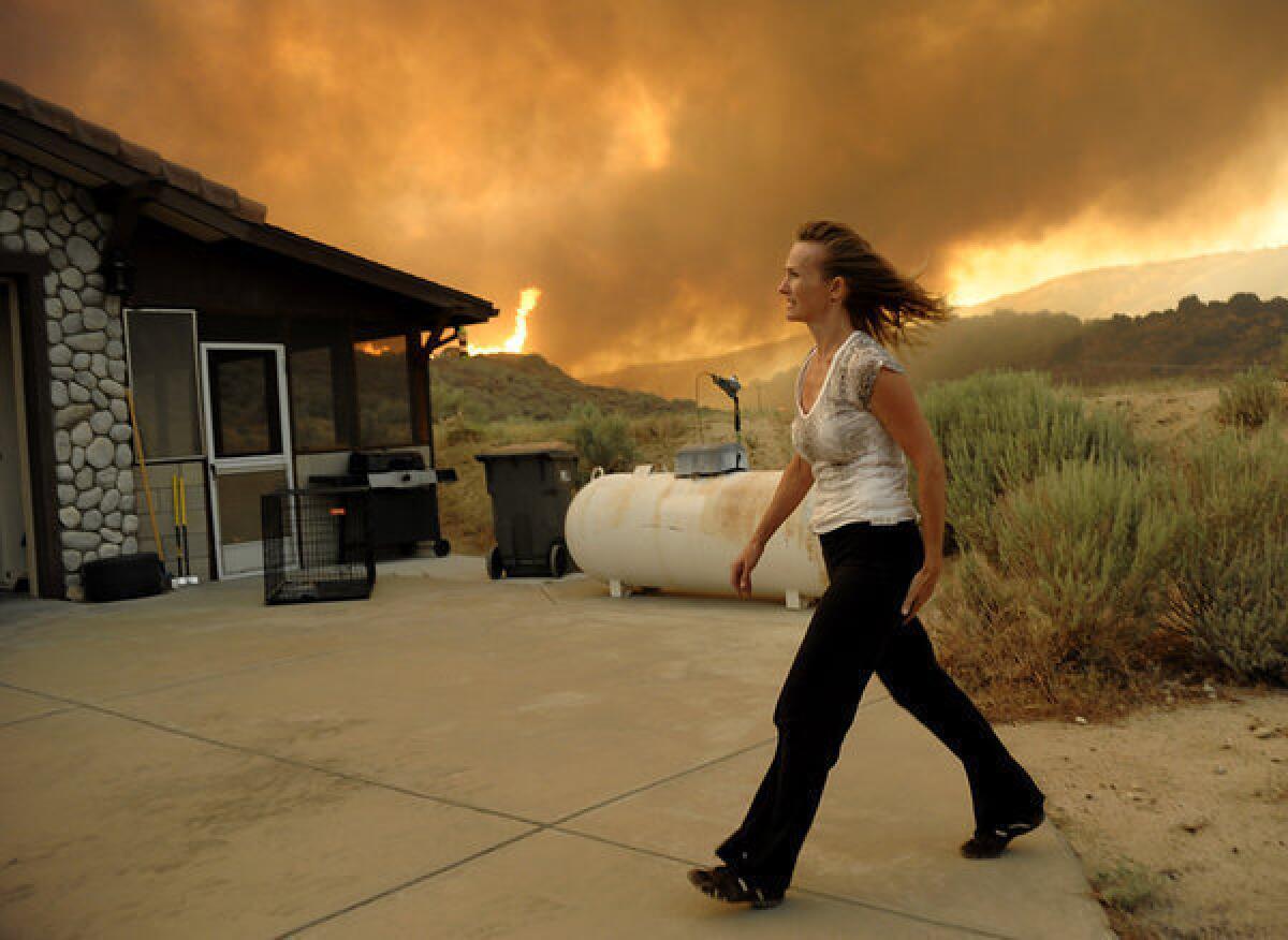 An unidentified woman watches as flames approach her home from a fast-moving wildfire near Palmdale.