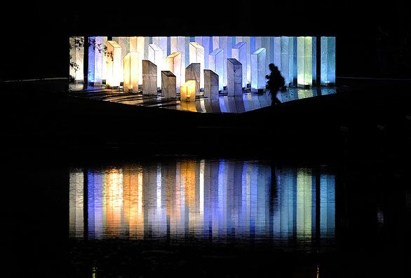 The silhouette of a visitor is seen as a light installation is reflected in a pond during the Luminale light festival Wednesday night. Various light, sound and media installations are on display around the city during the festival, which runs through Friday.