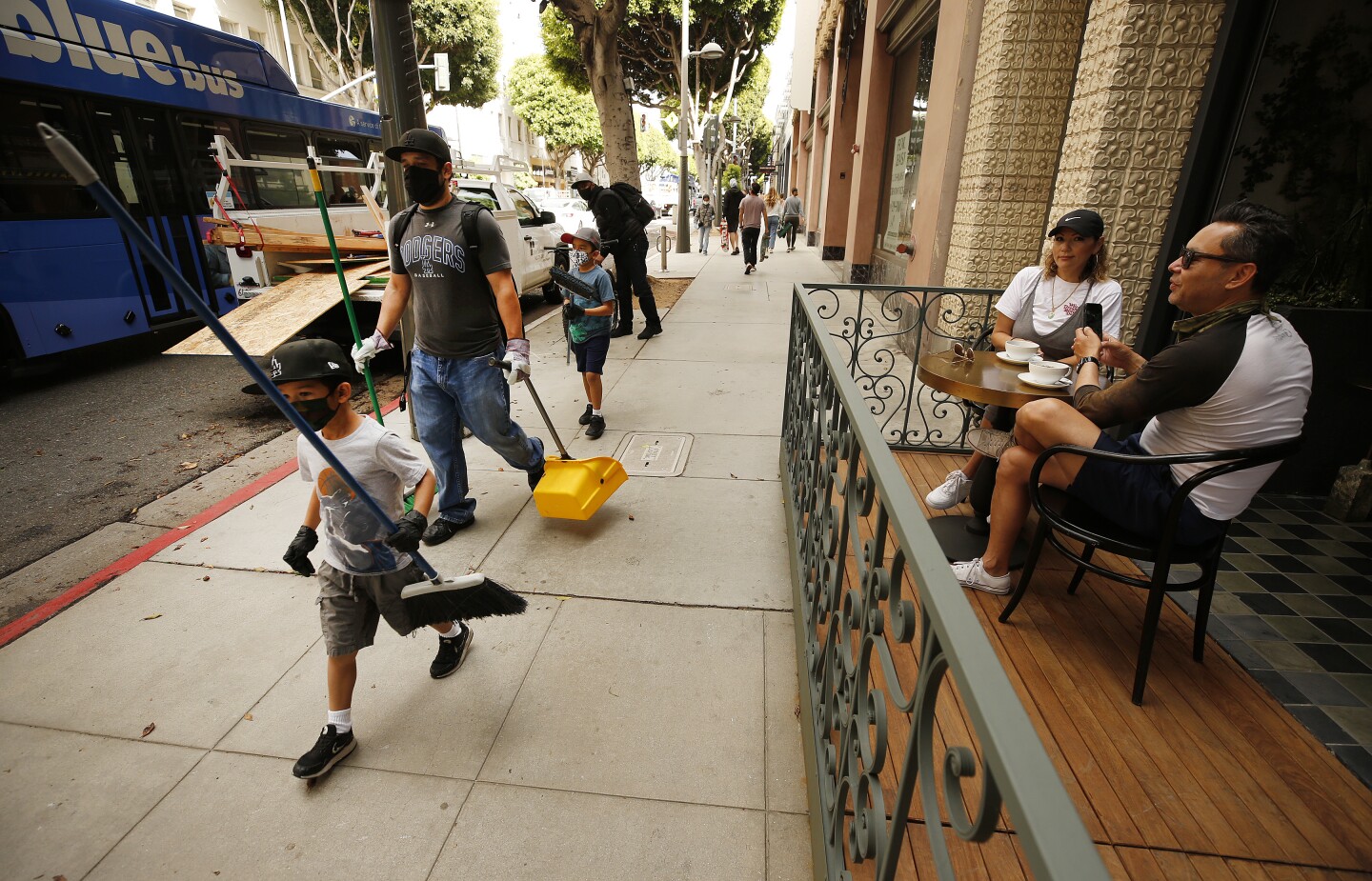 Gilbert Haro with sons Richard, 8, and James, 6, walk 4th street in the upscale shopping district of Santa Monica Monday morning looking to help cleanup after looters destroyed numerous stores.
