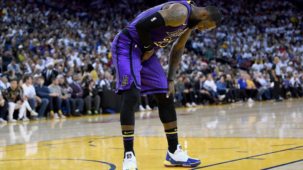 Lakers forward LeBron James (23) leans over in pain after injuring his groin against the Golden State Warriors on Dec. 25.