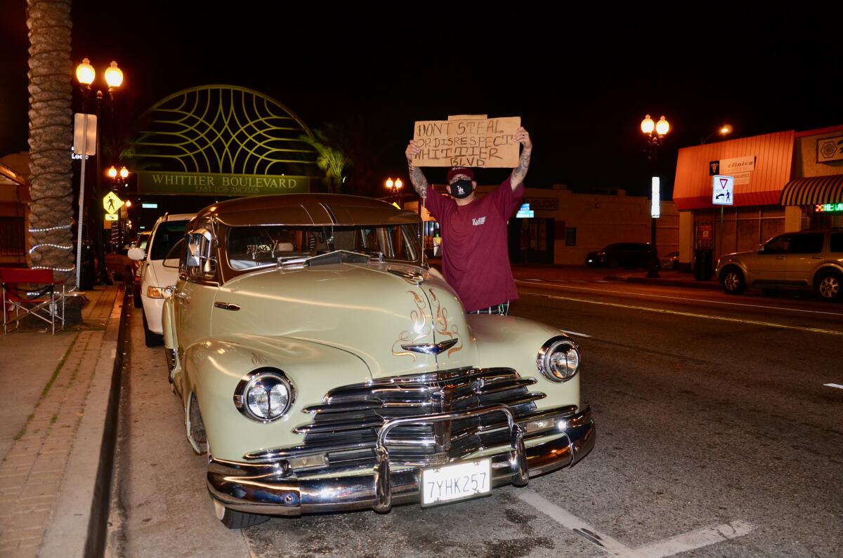 Stephan Ruelas, a member of the Klique Car Club, holds a sign on Whittier Boulevard