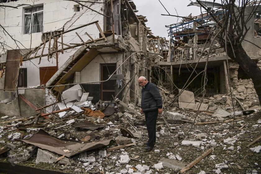 An man stands in front of a destroyed house