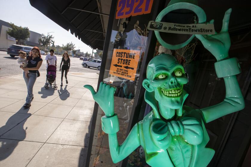 BURBANK, CA - October 10, 2022 - Customers walk past a window on their way into the Halloween Town store Monday, Oct. 10, 2022 in Burbank, CA. (Brian van der Brug / Los Angeles Times)