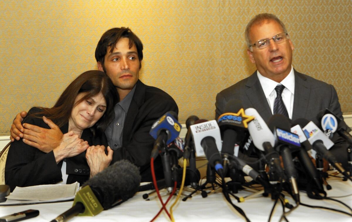 Michael Egan, center, hugs his mother, Bonnie Mound, as attorney Jeffrey Herman announces sexual abuse lawsuits against four Hollywood executives at a news conference in April 2014.