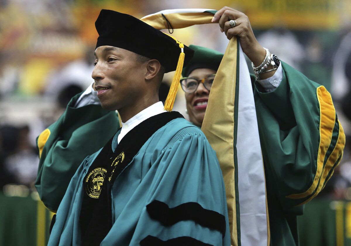 FILE - Norfolk State University President Javaune Adams-Gaston bestows Pharrell Williams with an honorary doctorate after he gave the commencement speech, Saturday, Dec. 11, 2021, in Norfolk, Va. In remarks made Monday, Jan. 17, 2022, during the Urban League of Hampton Roads’ annual Martin Luther King Jr. awards program, singer and music producer Williams challenged corporate America to “do more” by supporting entrepreneurs of color and adopting economic equity measures. (Stephen M. Katz/The Virginian-Pilot via AP, File)