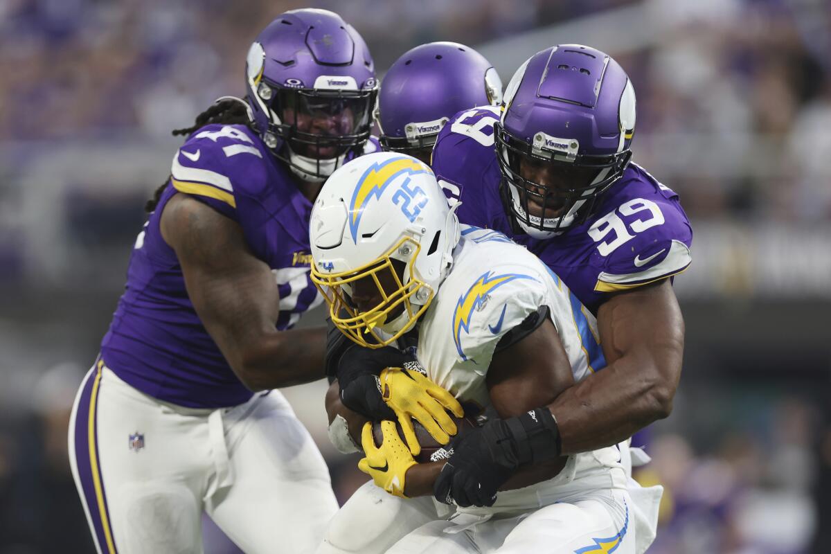 The Chargers' Joshua Kelley (25) is gang tackled by the Minnesota Vikings. 