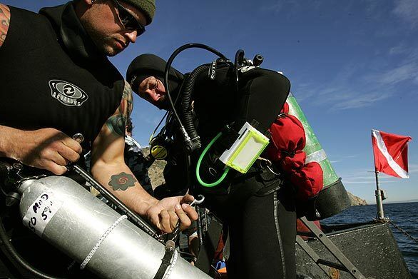 Donny Neal attaches a special dive tank to a harness worn by Paul Tattreau. The tank held a special nitrous oxide mixture that enabled them to spend more time at the bottom while reducing the chances of getting sick.