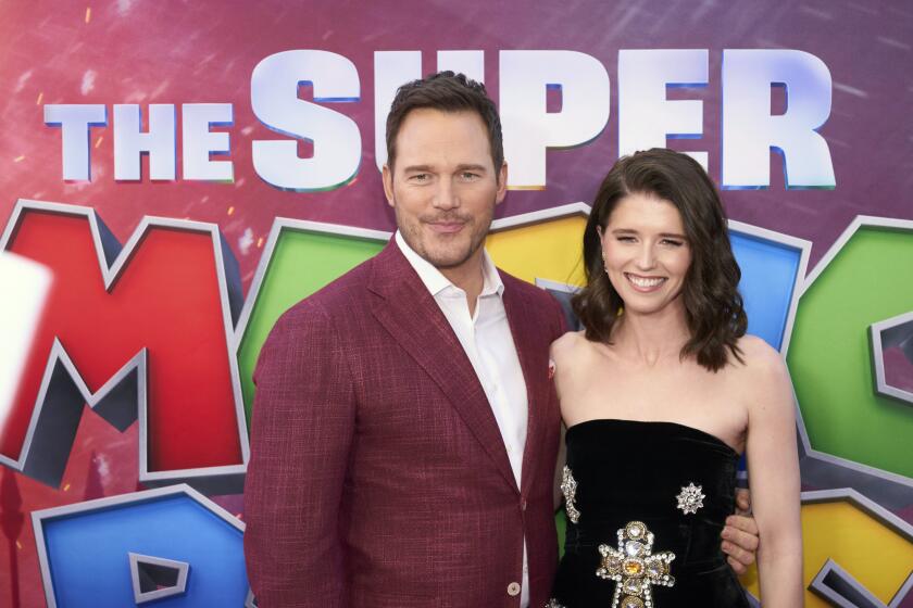 Chris Pratt and wife Katherine Schwarzenegger pose together while smiling at a movie premiere