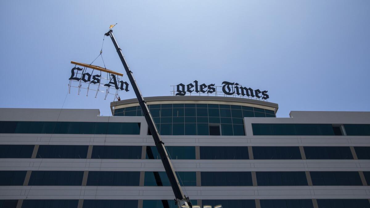 Workers hoist a new sign to the roof of the Los Angeles Times' new headquarters in El Segundo.