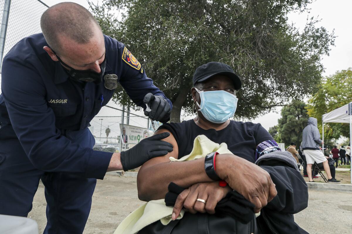 L.A. firefighter Jason Jasgur administers a COVID-19 vaccine to Althea Darby, 69, at a mobile vaccination site in South L.A.