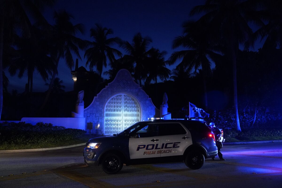 Un vehículo policial permanece frente a una entrada de la finca Mar-a-Lago del expresidente Donald Trump