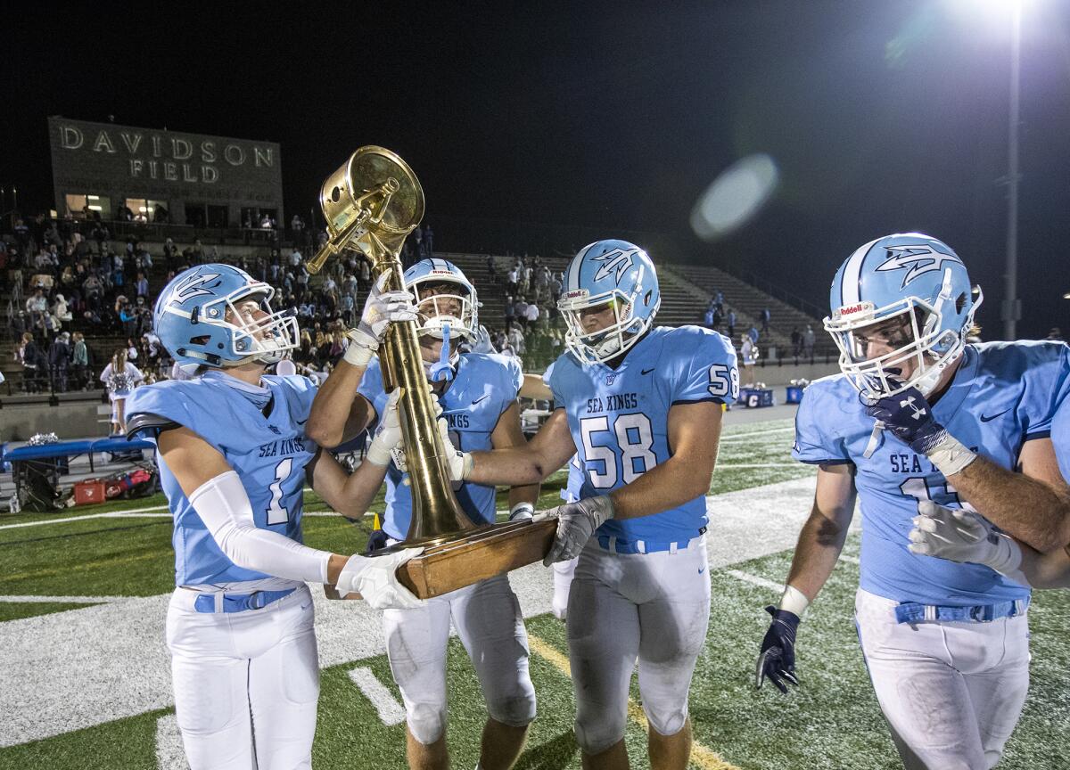 Corona del Mar's Max Lane, left, Tommy Griffin, Thomas Bouda and Ryan Zimmerman, right, hoist the Battle of the Bay trophy. 