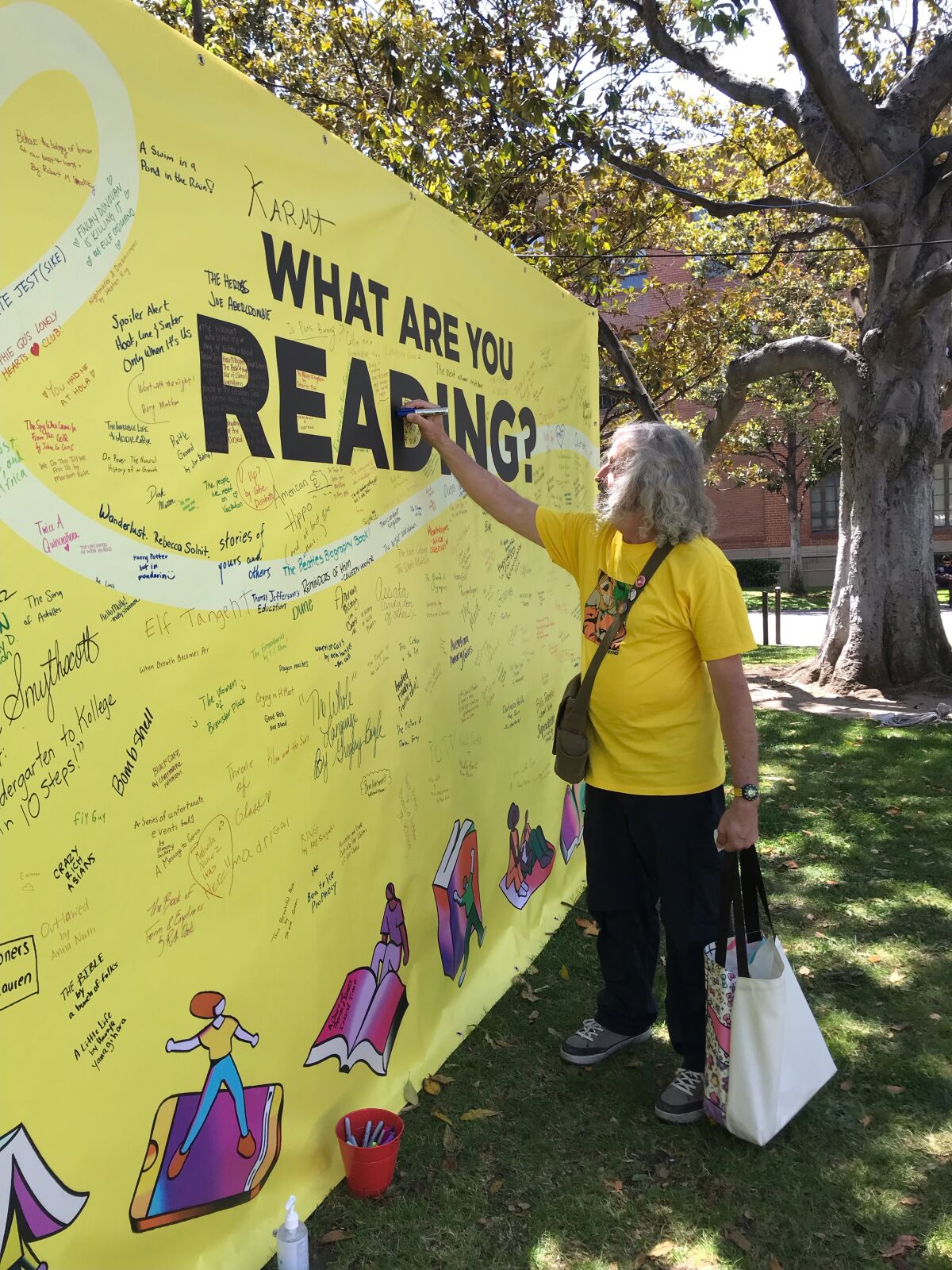 A man signs the "What are you reading?" banner at the Festival of Books.