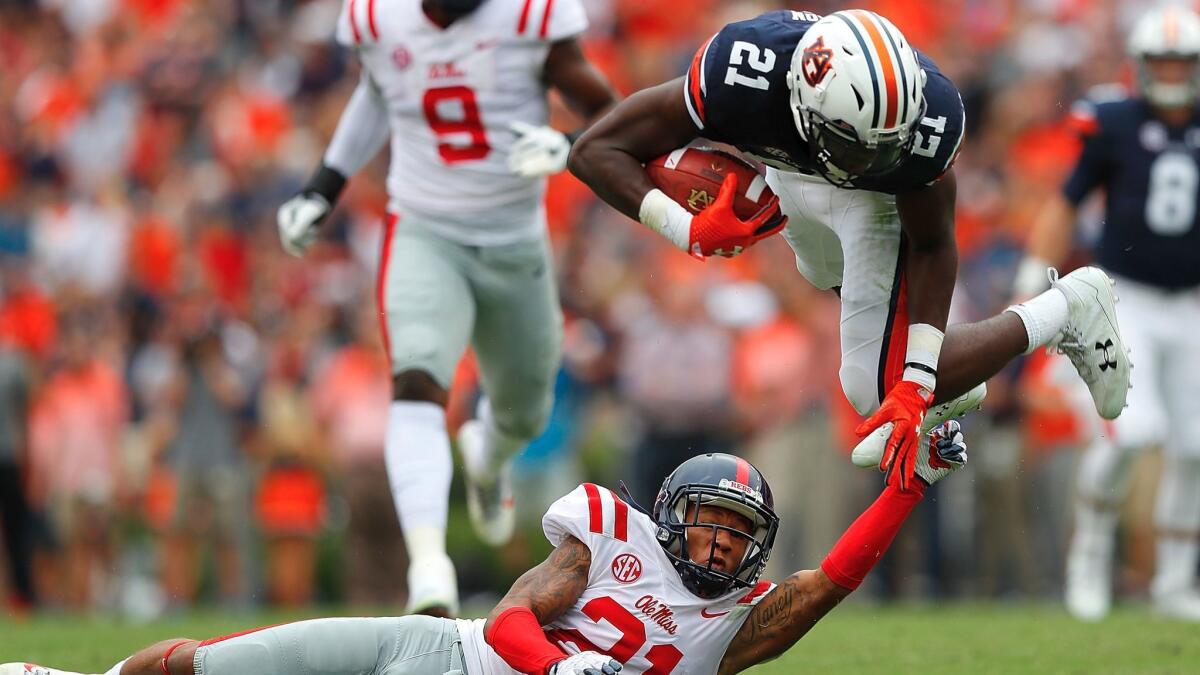 Auburn's Kerryon Johnson is tripped up as he leaps over Mississippi's Javien Hamilton on Oct. 7.