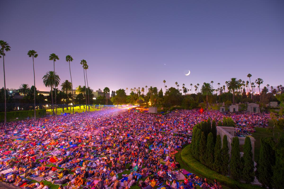 A crowd watches in a movie in a cemetery.