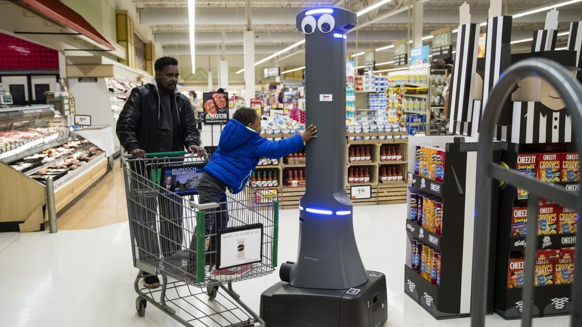 A child greets a robot named Marty as it monitors a Giant Food Stores grocery store in Harrisburg, Pa. The chain is putting the robots in all its stores.