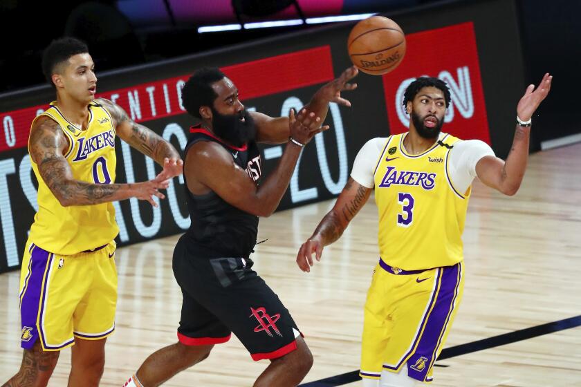Houston Rockets guard James Harden passes the ball while defended by Lakers forward Kyle Kuzma and forward Anthony Davis