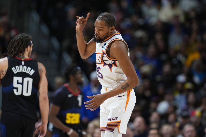 Phoenix Suns forward Kevin Durant gestures after hitting a 3-point basket against Denver Nuggets forward Aaron Gordon during the second half of an NBA basketball game Wednesday, March 27, 2024, in Denver. (AP Photo/David Zalubowski)