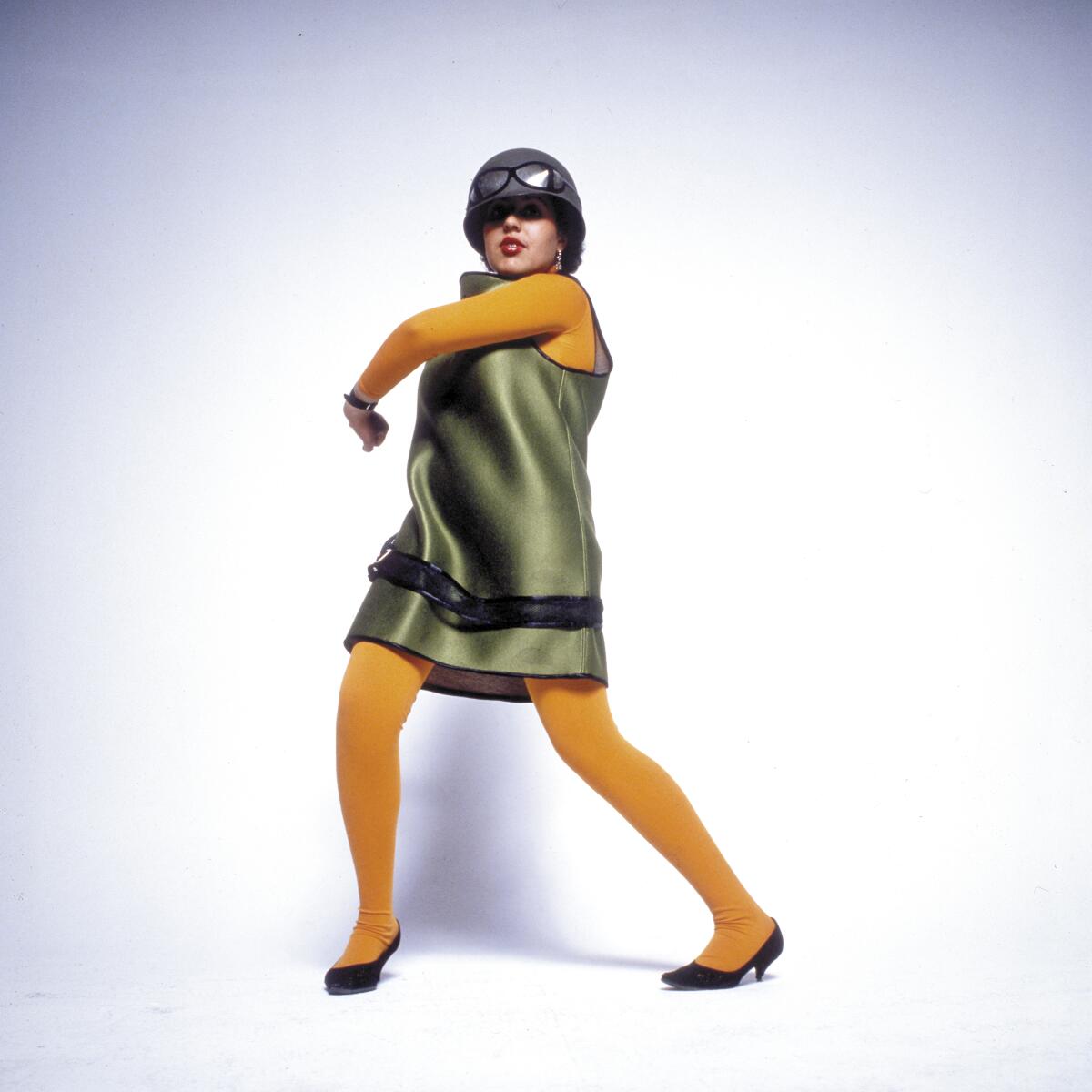 A woman in a green dress and yellow tights, wearing a helmet