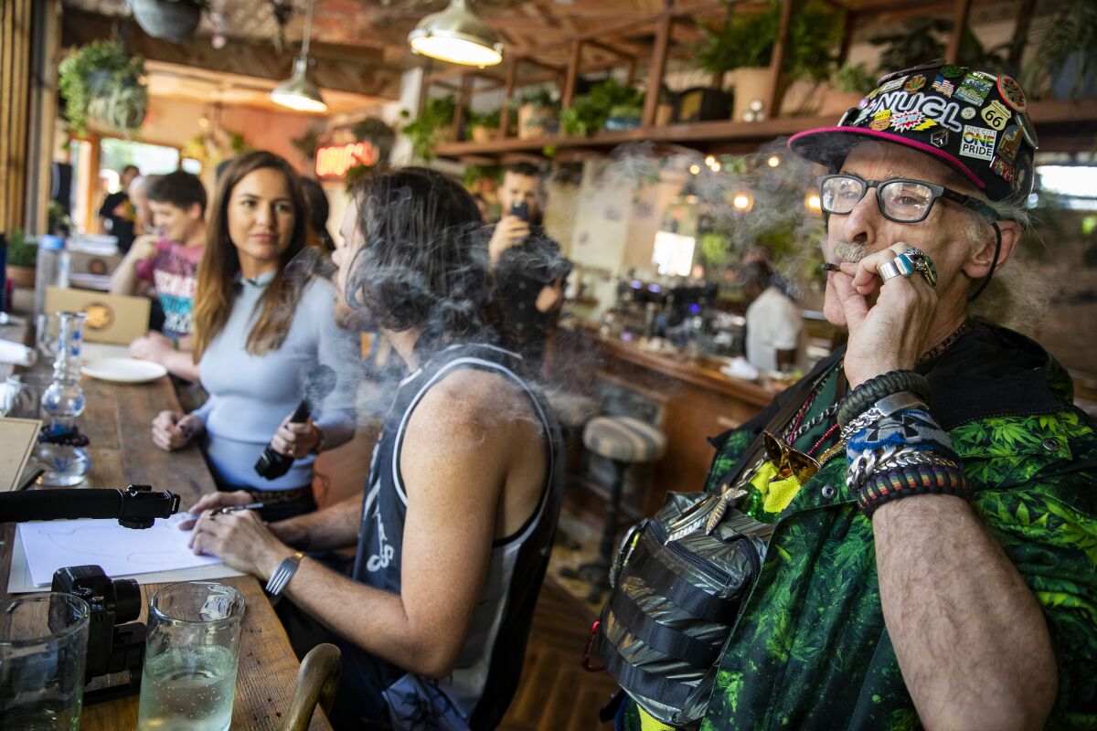 Richard Eastman, right, smokes a joint inside the Lowell Cafe on opening day in West Hollywood in  2019. 