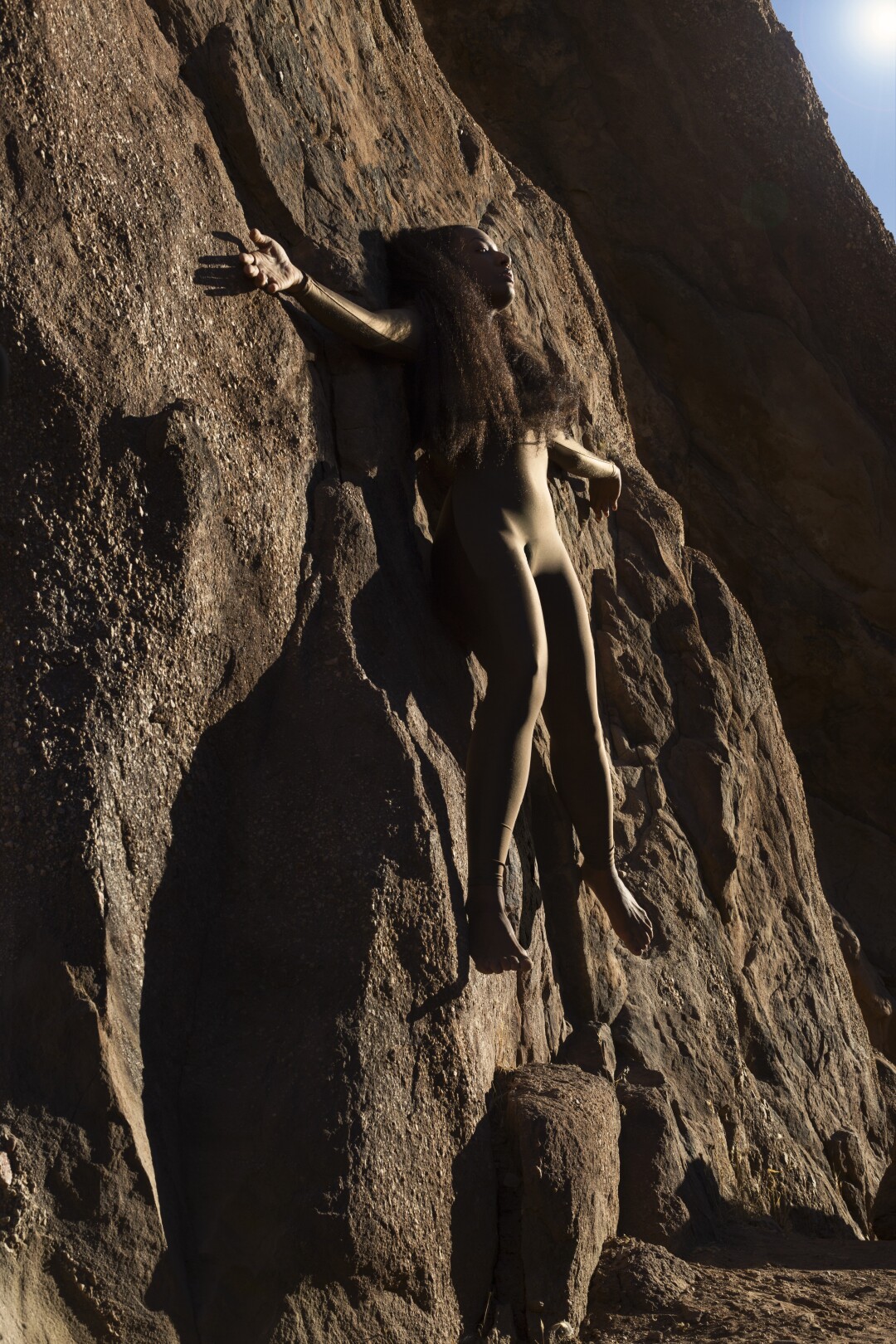 A woman seems to float against a wall of rock.