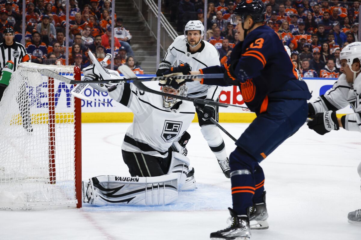 Kings goalie Jonathan Quick swats away the puck as Edmonton Oilers right wing Jesse Puljujarvi tries to deflect it.