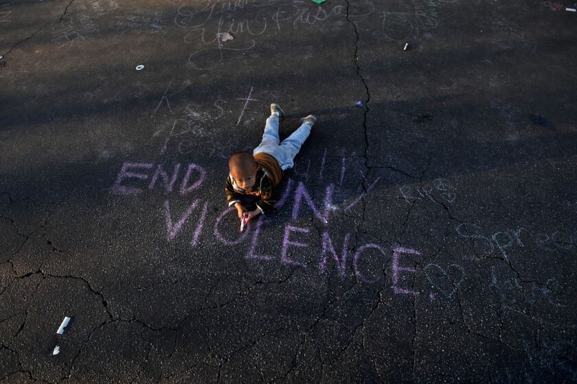 MONTEREY PARK, CA - JANUARY 26, 2023 - - Harry Su, 2, lays on the message, "End Gun Violence," at the memorial for 11 people who died in a mass shooting during Lunar New Year celebrations outside the Star Ballroom Dance Studio in Monterey Park on January 26, 2023. (Genaro Molina / Los Angeles Times)