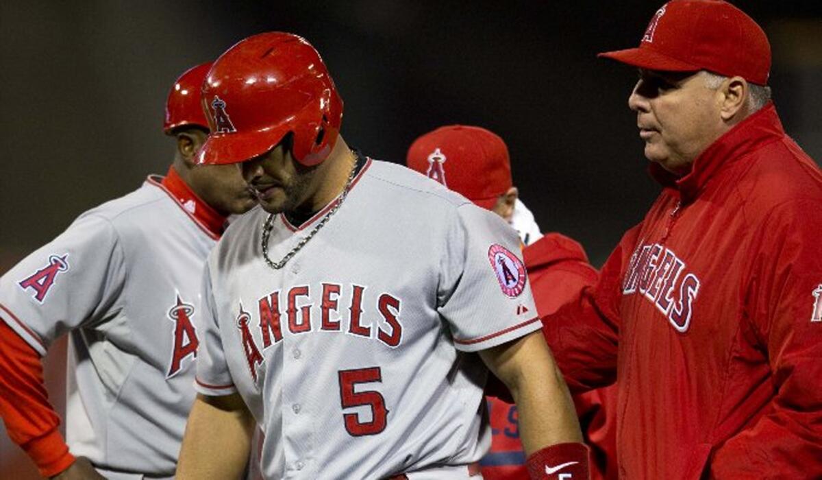 Angels first baseman Albert Pujols leaves the game with Manager Mike Scioscia after injuring his leg running to first base Wednesday night.