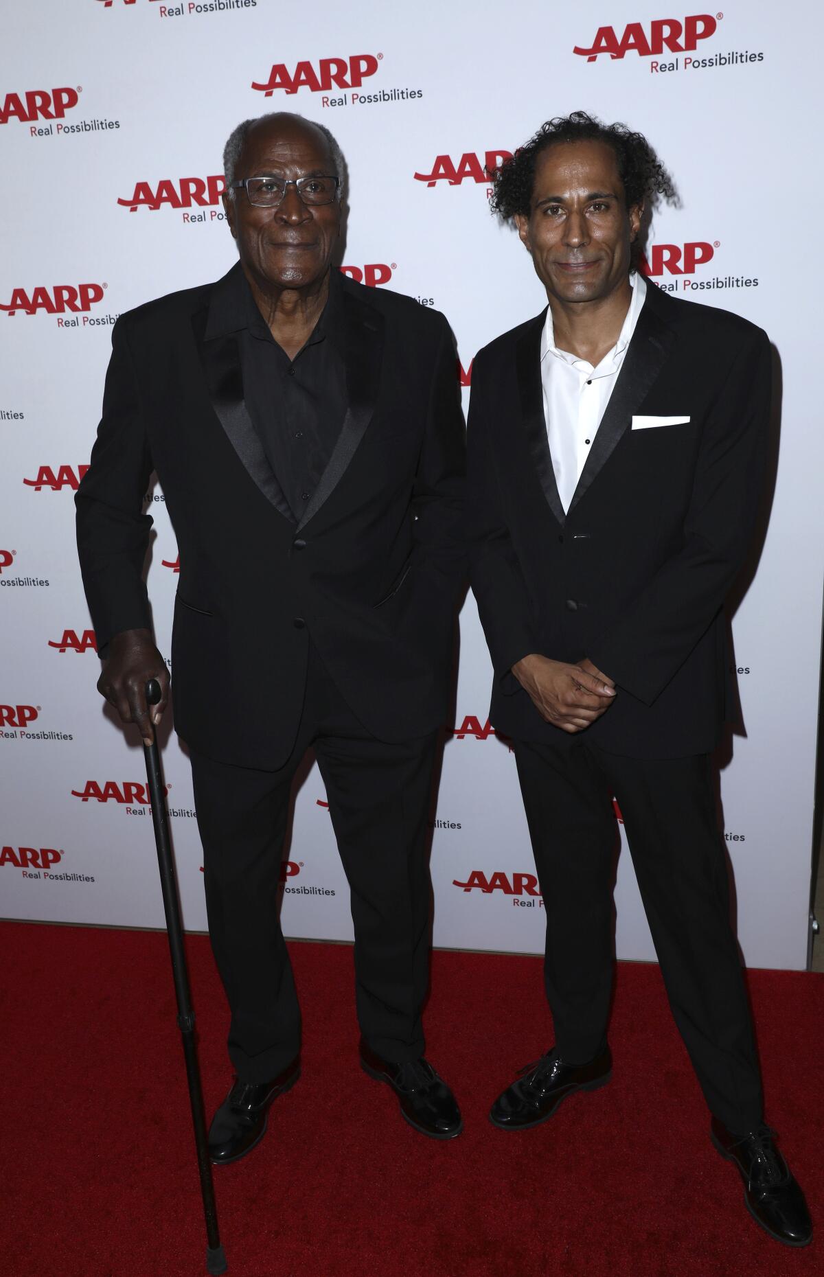 John Amos, left, and son K.C. Amos pose together on a red carpet in black formal attire