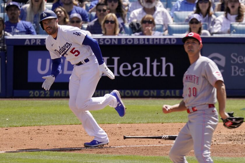 Los Angeles Dodgers' Freddie Freeman, left, runs to first after hitting a two RBI single.