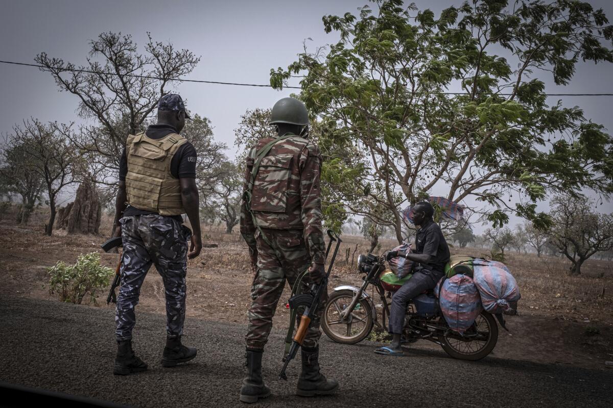 A police officer and a soldier from Benin stop a motorcyclist at a checkpoint outside Porga, Benin.