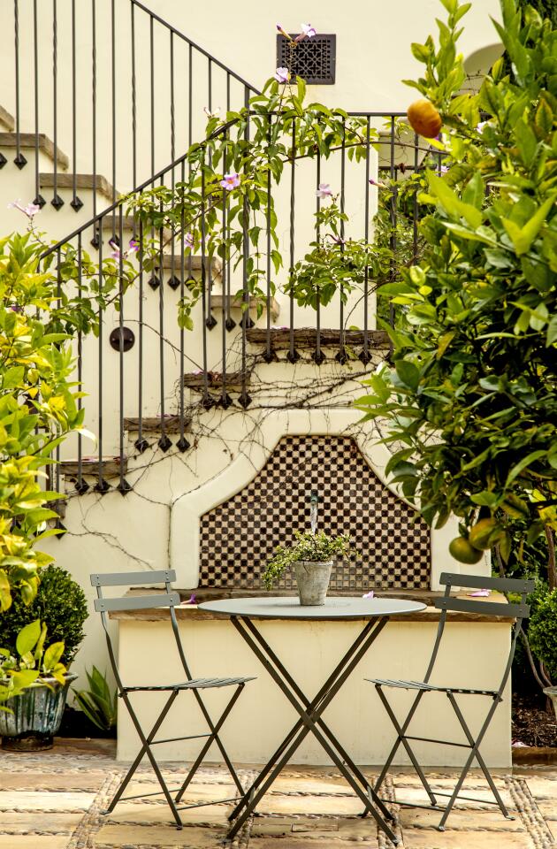 A tiled fountain provides a charming backdrop and calming sound to a table and chairs in the central court.