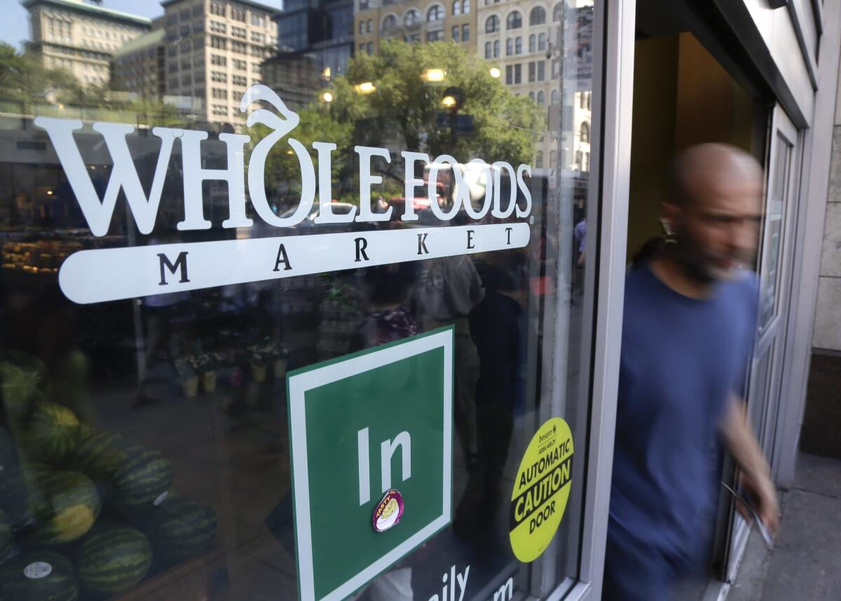 A shopper leaves a Whole Foods Market in New York in June.
