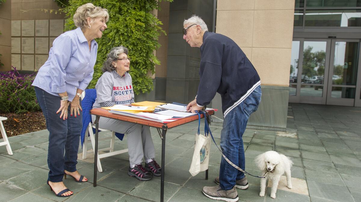 Newport Beach resident Stanley Kay, right, shares a laugh with volunteers Joy Brenner, left, and Linda Oeth, center, after signing a petition to recall Councilman Scott Peotter at Newport Beach Public Library.