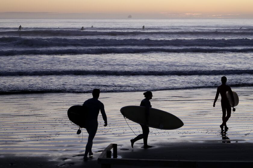 Surfers prepare to enter the water at Sumner Beach as level four COVID-19 restrictions are eased in Christchurch, New Zealand, Tuesday, April 28, 2020. New Zealand eased its strict lockdown restrictions to level three at midnight to open up certain sections of the economy but social distancing rules will still apply. (AP Photo/Mark Baker)