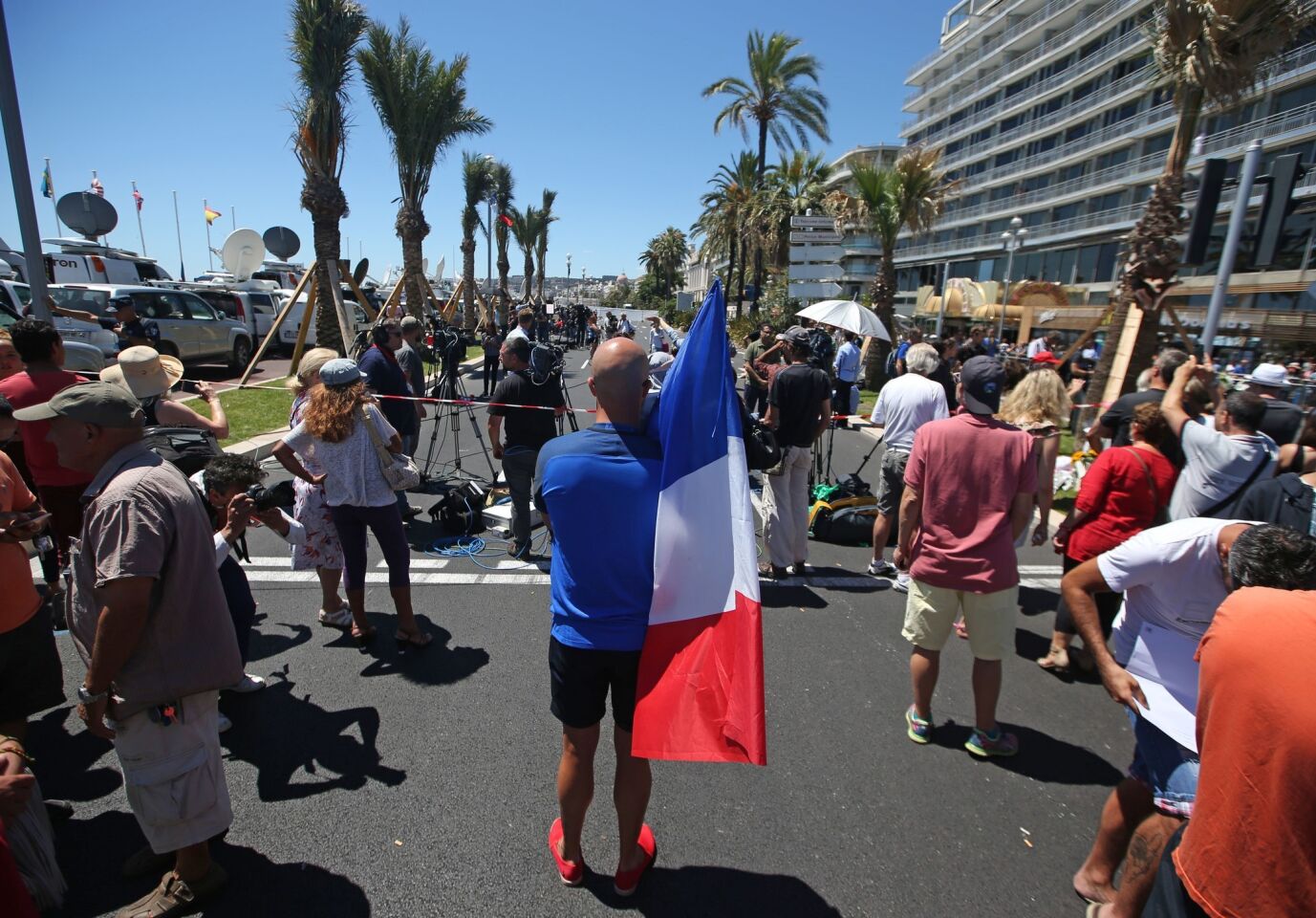 A man holding the French national flag stands near the site of the truck attack in the French resort city of Nice, France.