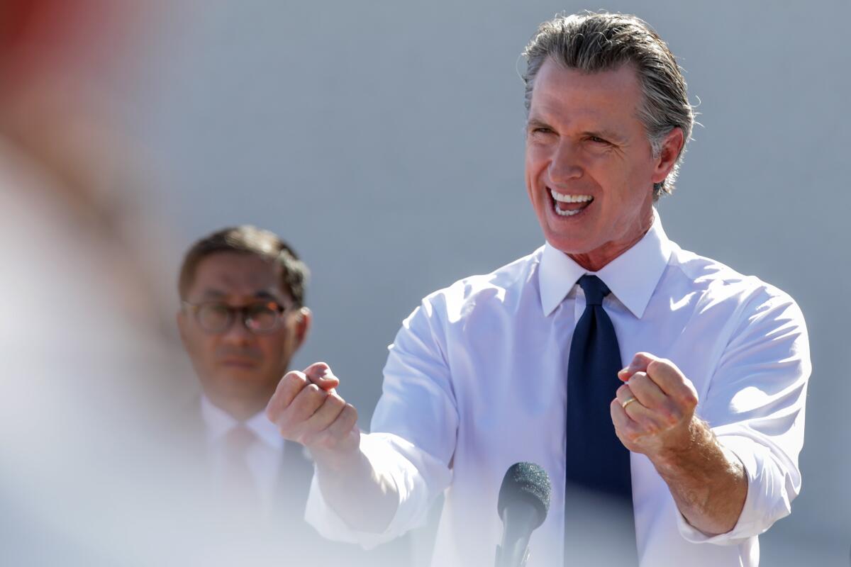 Gov. Gavin Newsom gestures with two fists while speaking at a podium