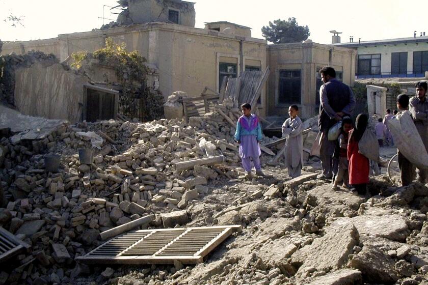 FILE - In this Wednesday, Oct. 17, 2001 file photo, Afghans look at the debris of a destroyed house in Kabul, Afghanistan after heavy U.S. led military strikes. Associated Press correspondent Amir Shah was AP's eyes and ears in Afghanistan after the 9/11 attacks, when all foreigners were ordered to leave. His assignment was dangerous, delicate and often terrifying. (AP Photo/Amir Shah, File)